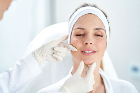 Plastic surgeon inspecting the face of a female patient